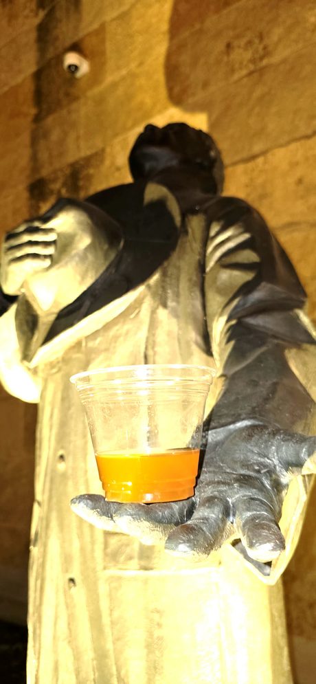 Top Shelf night: bronze statue uplit against limestone, holding a real glass of beer