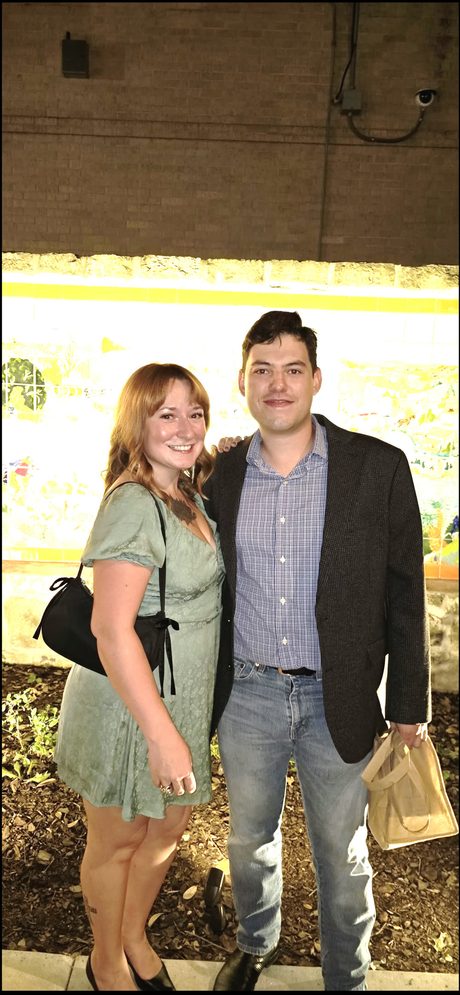 Top Shelf night: couple posing together in front of a lit vendor booth