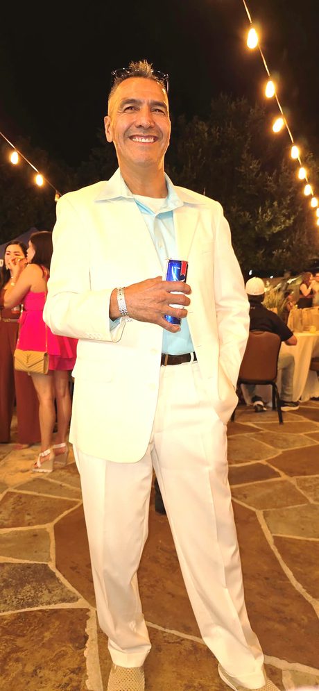 Top Shelf night: guest in a cream suit with a drink under the string lights
