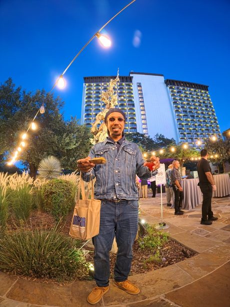 Top Shelf night: guest at blue hour under the string lights, hotel behind